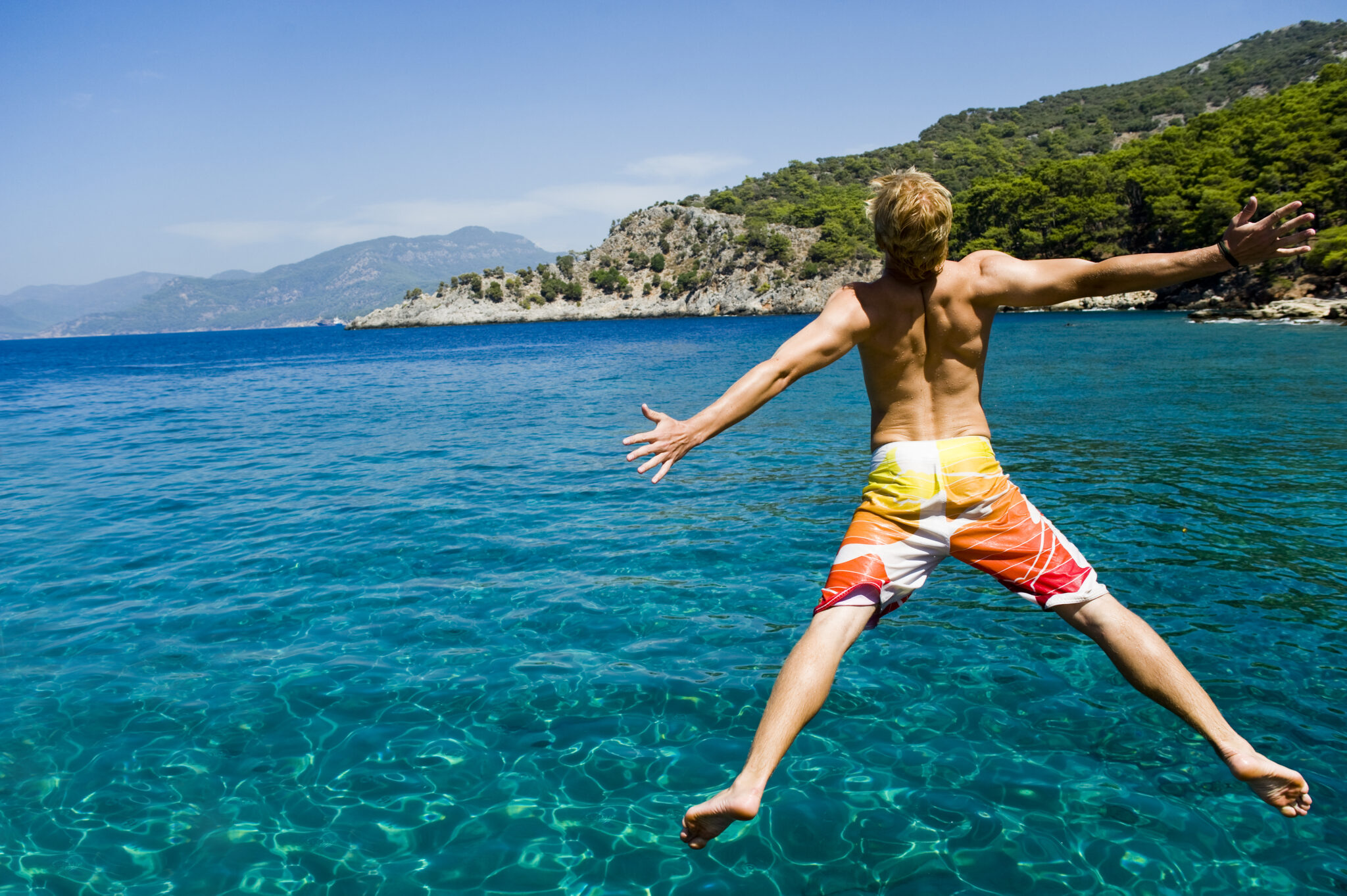 Young,Man,Jumping,Off,A,Boat,,Enjoying,The,Freedom,Of