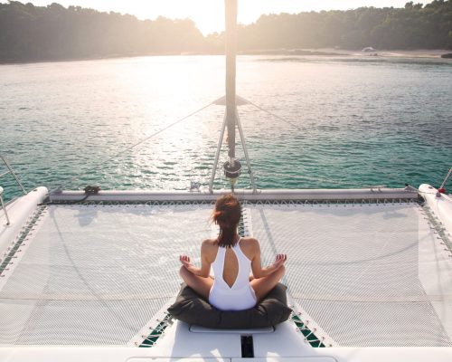 Women,Wear,White,Swimsuits.,Meditation,On,A,Catamaran,Sailboat.,Private